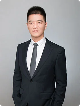 Portrait of David, the Marketing Director, wearing a formal black suit and tie, standing confidently.