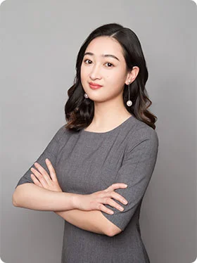 Portrait of Melody, the Sourcing Manager, wearing a grey dress and smiling with her arms crossed.
