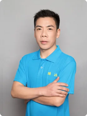 Portrait of Simon, the QC Manager, in a blue polo shirt, standing confidently with arms crossed.
