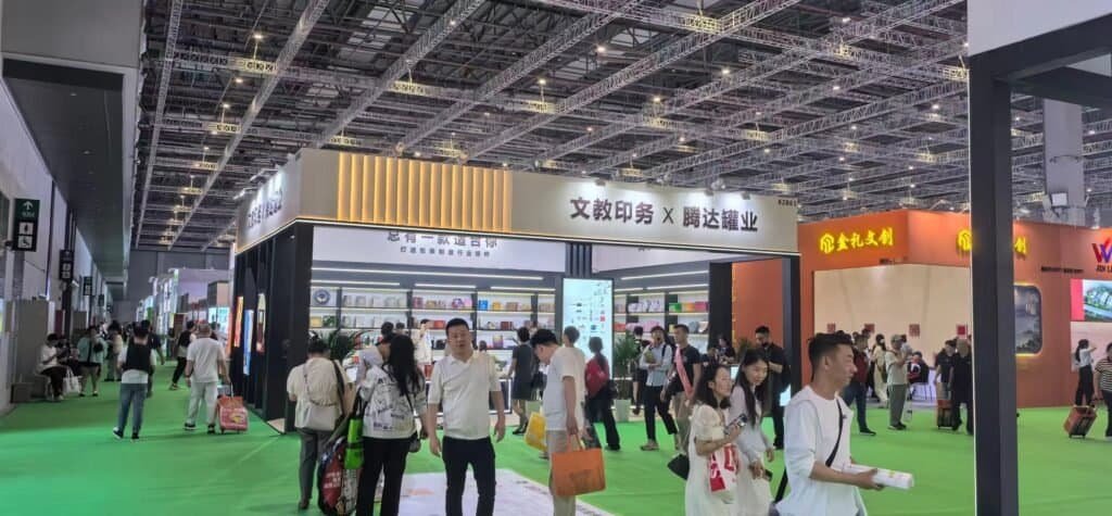 International client inspecting tin box printing and lid fit at TDTIN exhibition booth