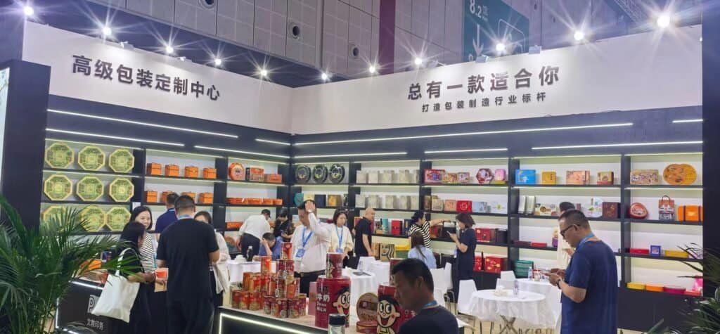 TDTIN sales manager discussing custom tin box samples with visitor at trade show