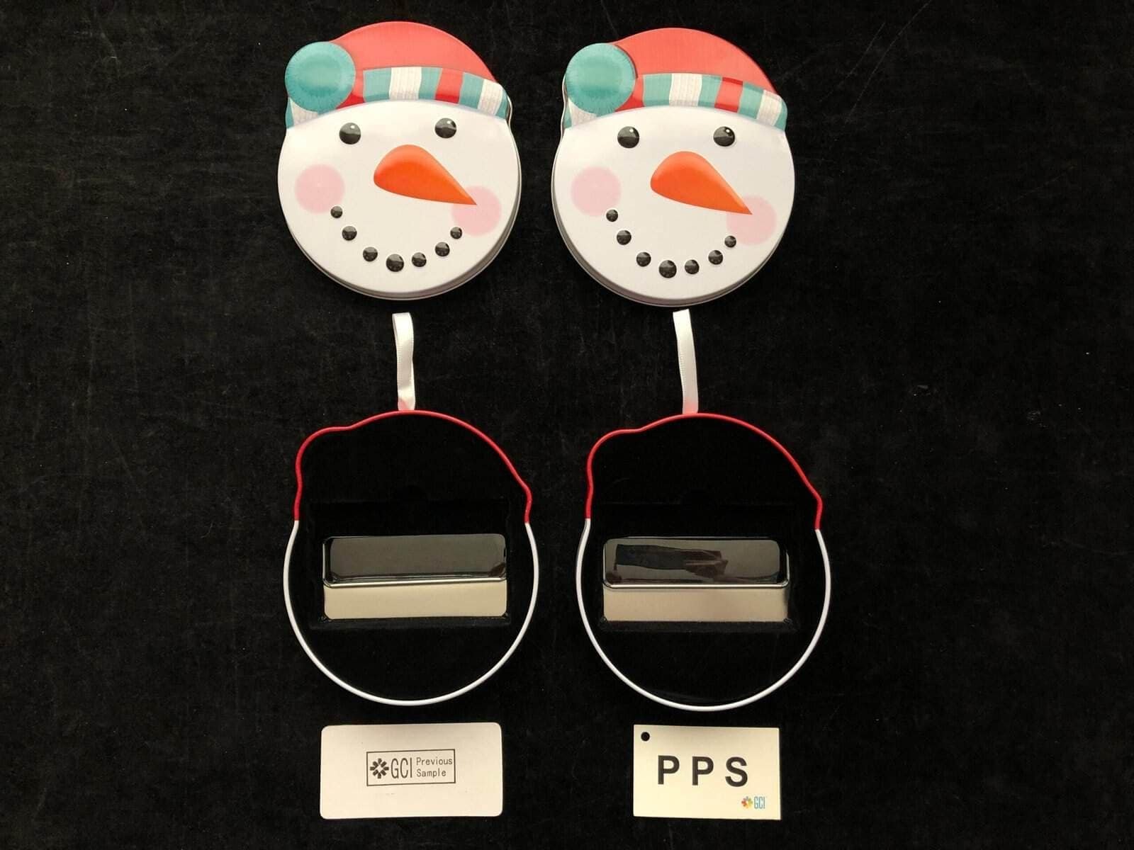 Two open snowman-shaped tins displayed side by side, showing the decorated lids and interior inserts