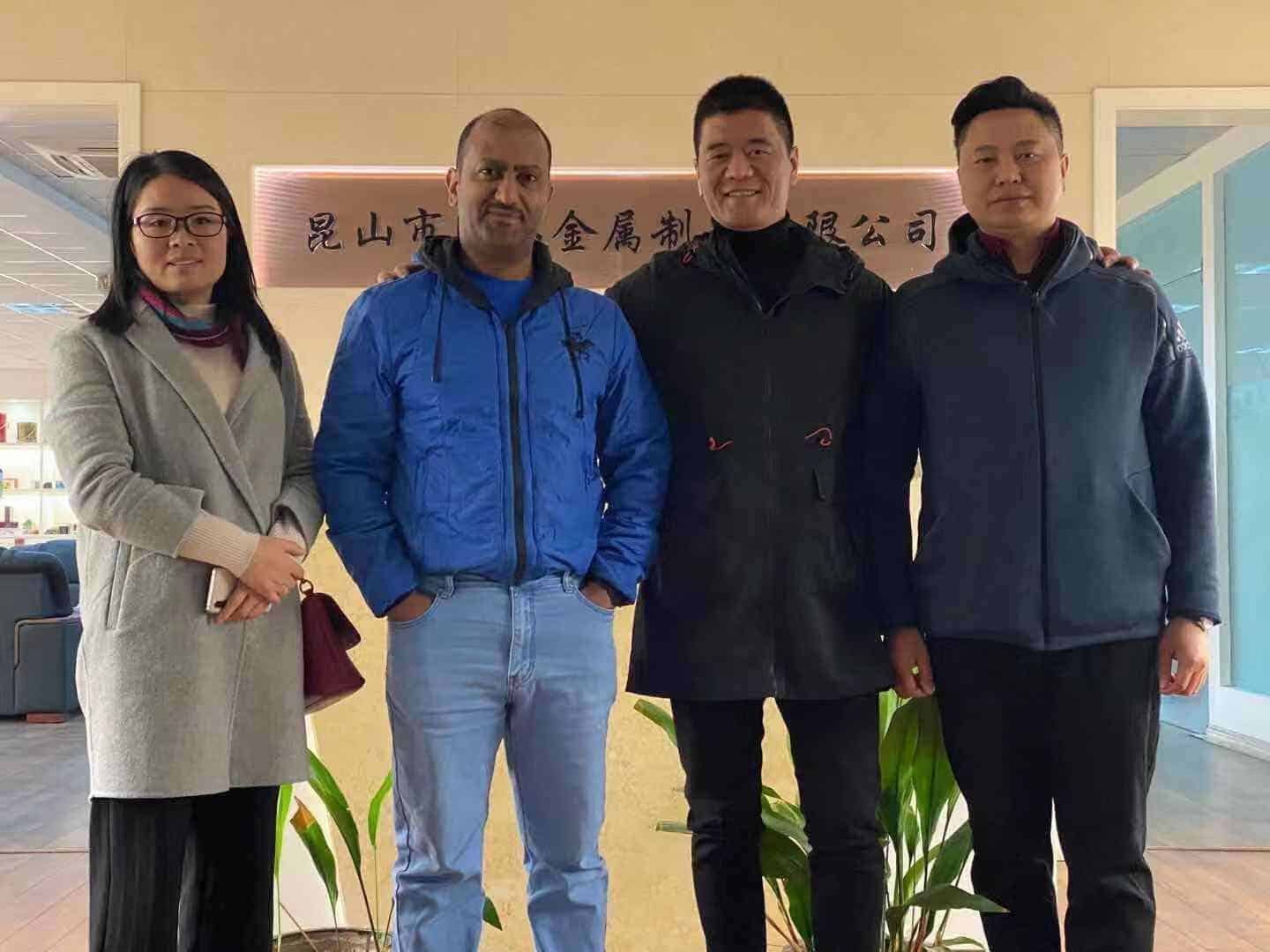 A visiting customer posing with three TDTIN team members in front of the company sign