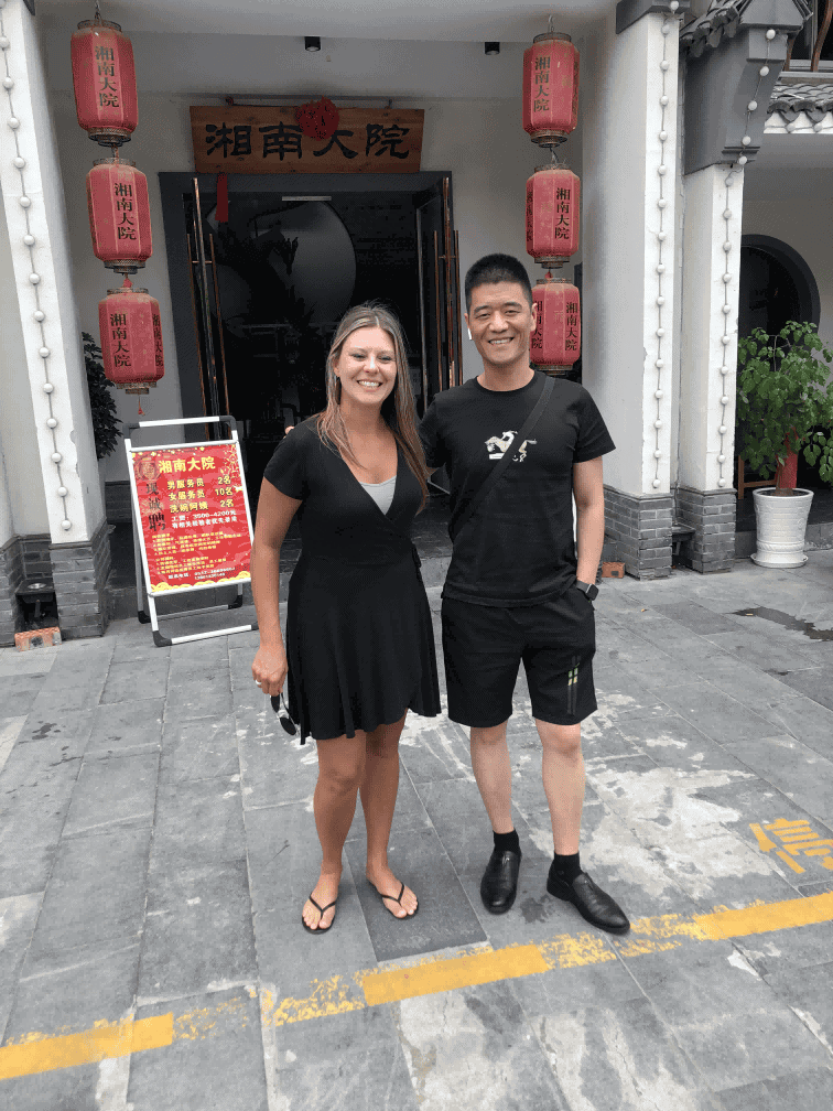 Visitor posing with a TDTIN team member outside a building